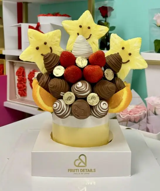 Classic fruit bouquet with smiling pineapple stars, chocolate-covered strawberries, and orange slices — handcrafted by Frutidetails Miami