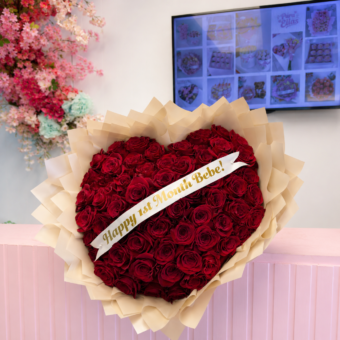 Heart-shaped bouquet of 60-65 natural red roses with elegant wrapping and personalized ribbon for anniversaries and romantic occasions.